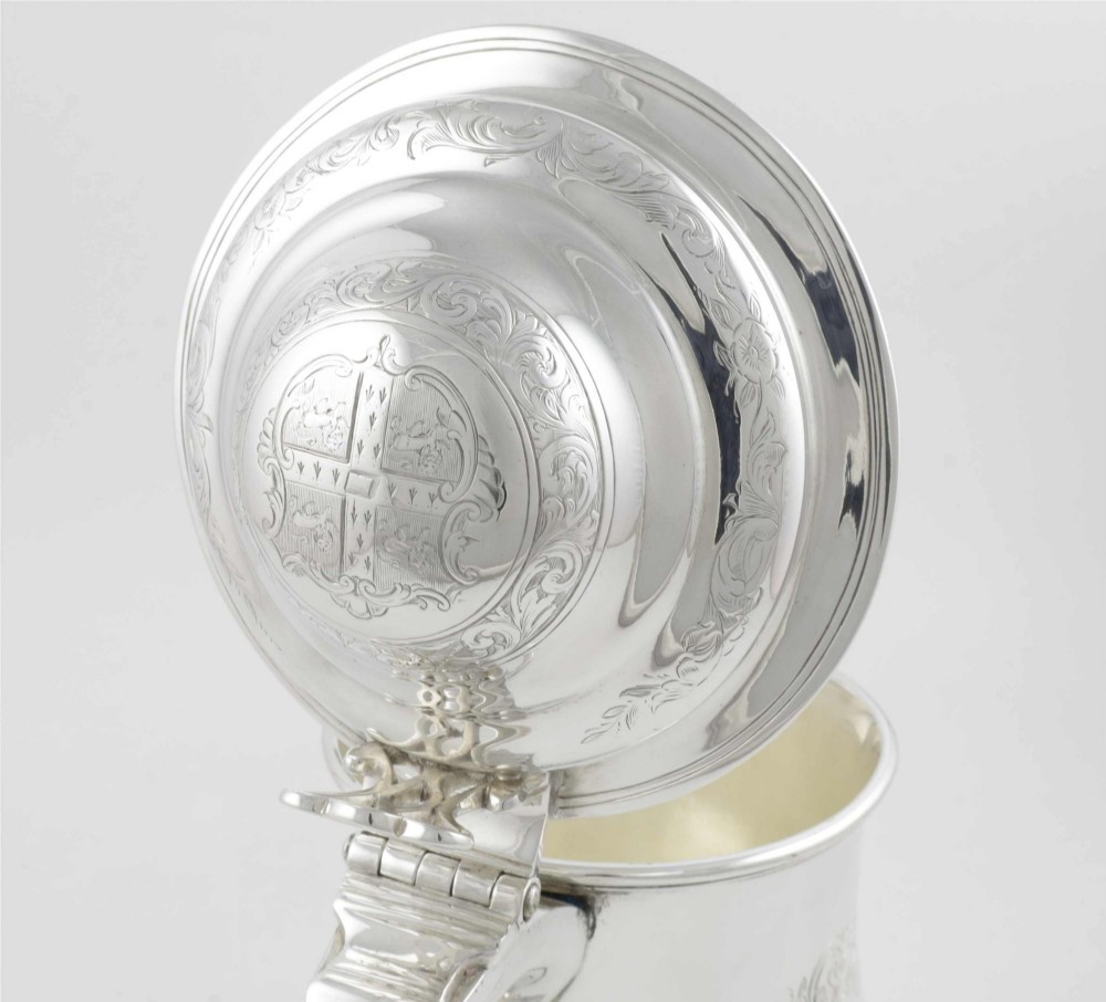 An engraved silver lidded jug featuring a hinged cap, scrolling handle, and foliate engraving across the body. View XIV