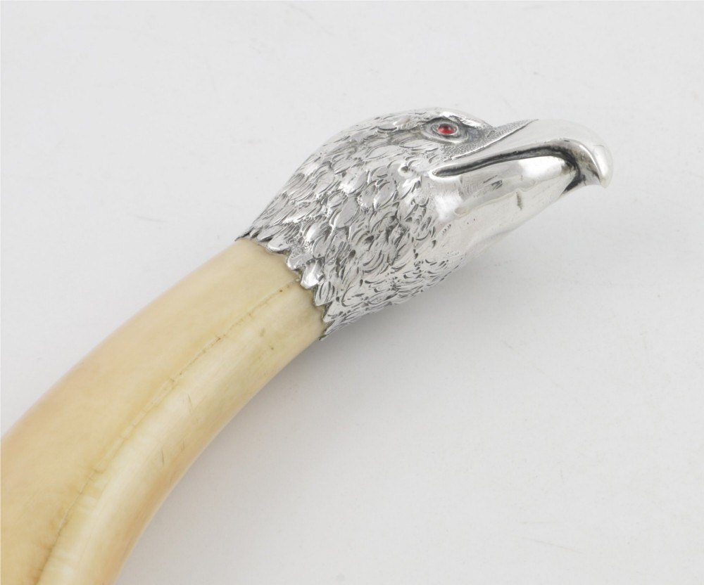 An antique cigar cutter crafted from a curved cream-coloured boar tusk fitted with a cast silver eagle head terminal and a silver cutting mechanism at the opposing end. View VI