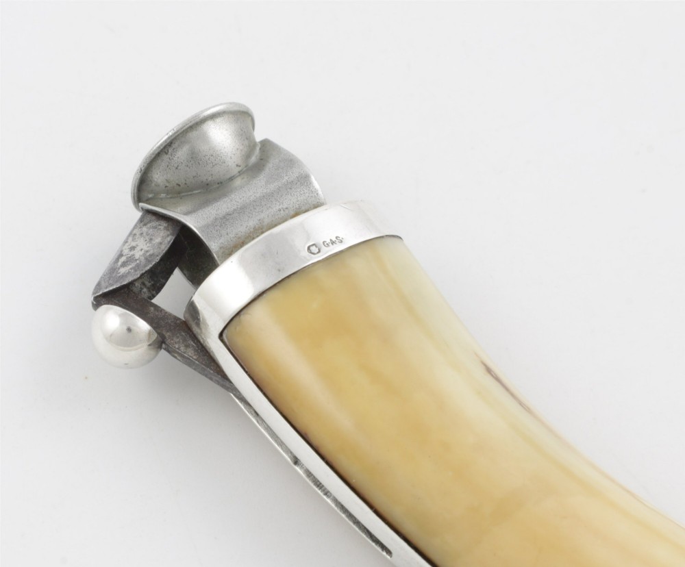 An antique cigar cutter crafted from a curved cream-coloured boar tusk fitted with a cast silver eagle head terminal and a silver cutting mechanism at the opposing end. View VIII