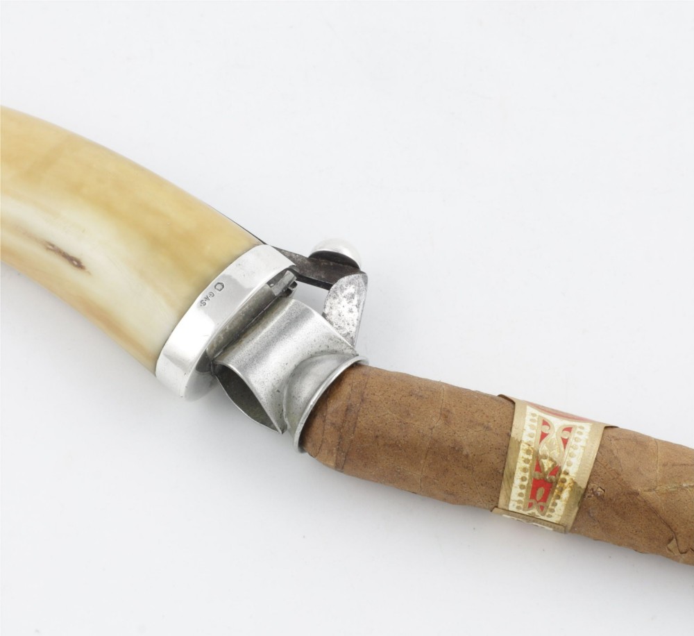 An antique cigar cutter crafted from a curved cream-coloured boar tusk fitted with a cast silver eagle head terminal and a silver cutting mechanism at the opposing end. View XII