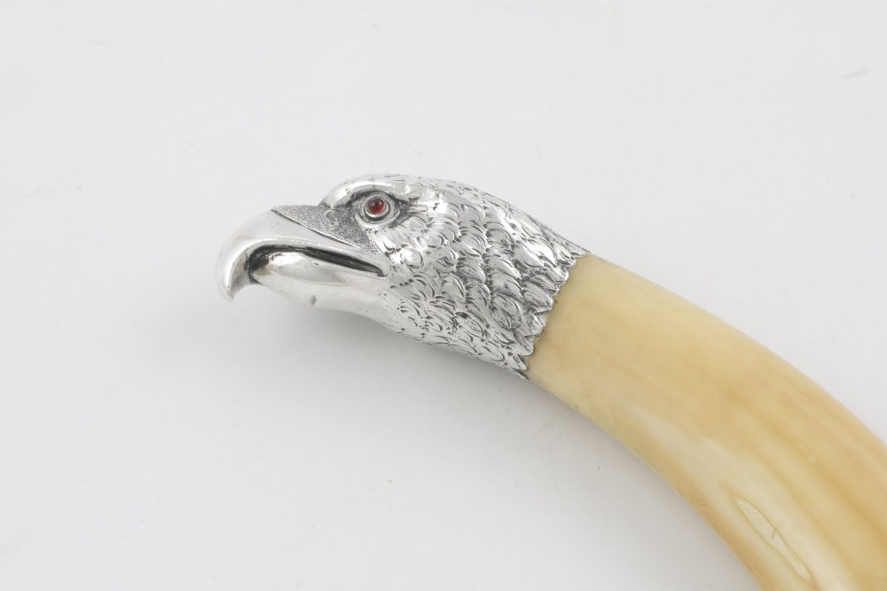 An antique cigar cutter crafted from a curved cream-coloured boar tusk fitted with a cast silver eagle head terminal and a silver cutting mechanism at the opposing end. View XIV