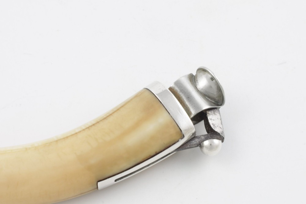 An antique cigar cutter crafted from a curved cream-coloured boar tusk fitted with a cast silver eagle head terminal and a silver cutting mechanism at the opposing end. View XV