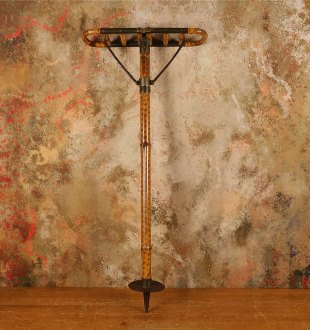 A late 19th-century bamboo shooting stick featuring a folding seat handle, metal support struts, and a spiked metal base.