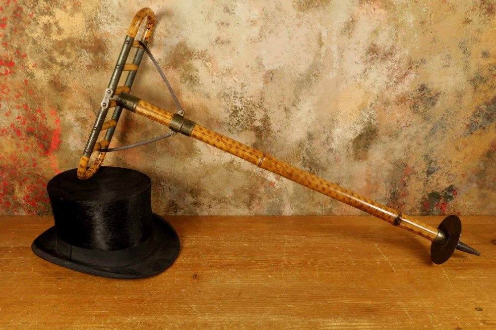 A late 19th-century bamboo shooting stick featuring a folding seat handle, metal support struts, and a spiked metal base. View II