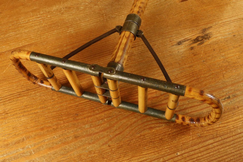 A late 19th-century bamboo shooting stick featuring a folding seat handle, metal support struts, and a spiked metal base. View X