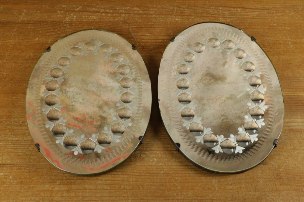 A pair of oval glass sorcerer mirrors featuring central dark reflections surrounded by a border of etched botanical motifs and raised convex glass lenses. View V