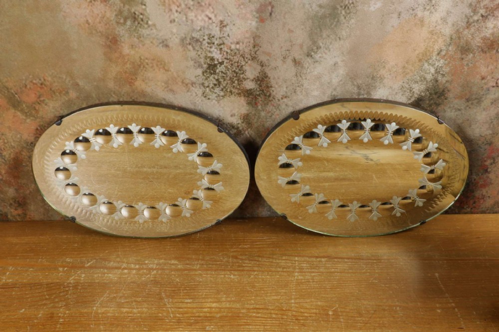 A pair of oval glass sorcerer mirrors featuring central dark reflections surrounded by a border of etched botanical motifs and raised convex glass lenses. View X