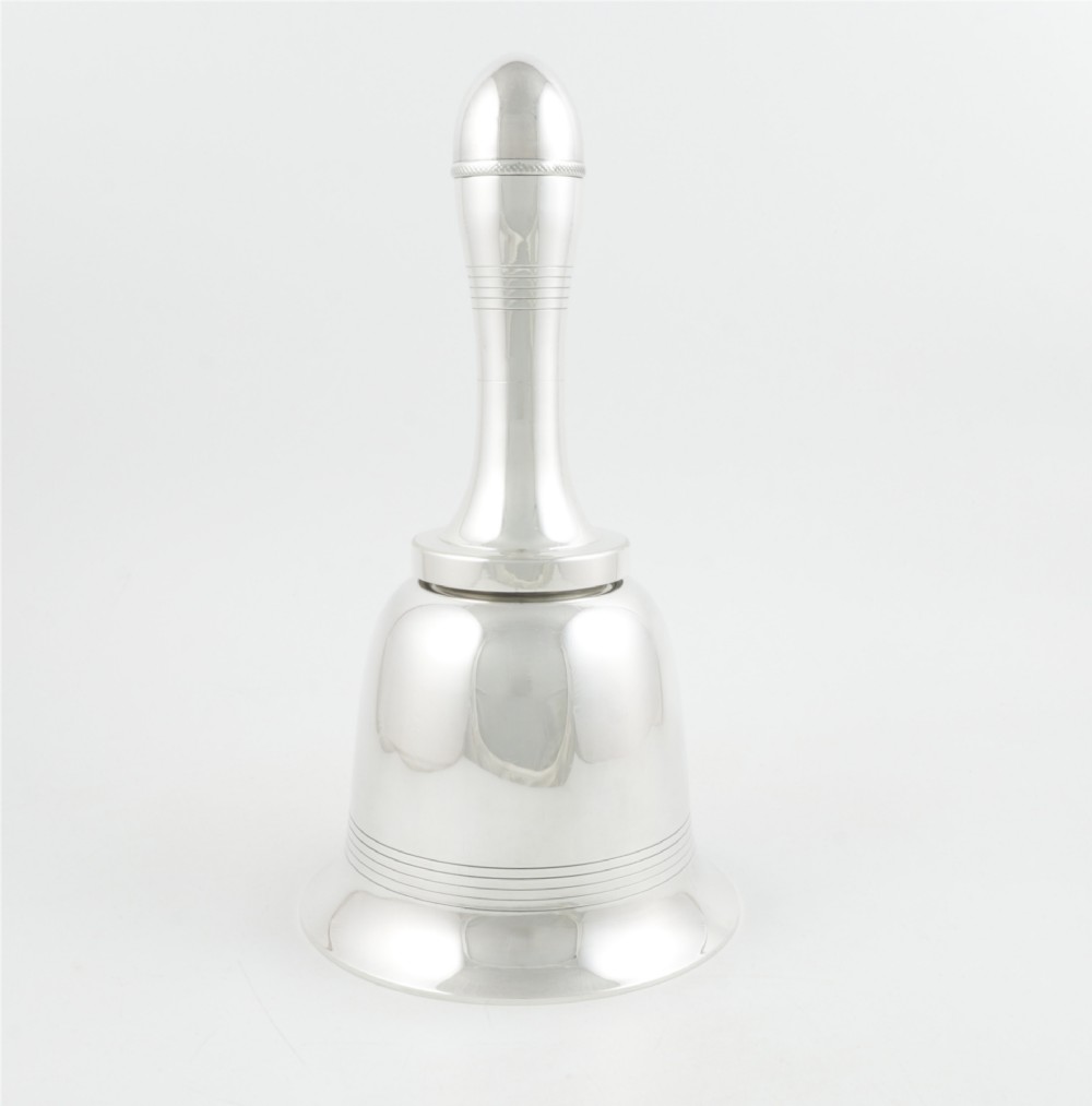 A silver plated novelty cocktail shaker in the shape of a handbell with a smooth turned handle and incised line detailing.