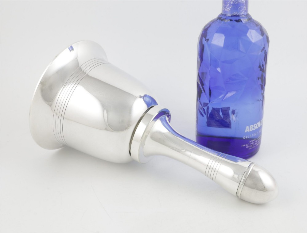 A silver plated novelty cocktail shaker in the shape of a handbell with a smooth turned handle and incised line detailing. View III