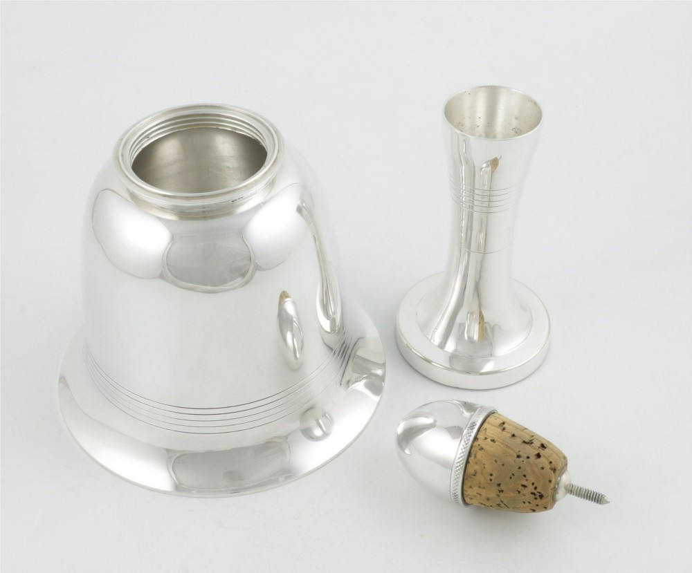 A silver plated novelty cocktail shaker in the shape of a handbell with a smooth turned handle and incised line detailing. View VI