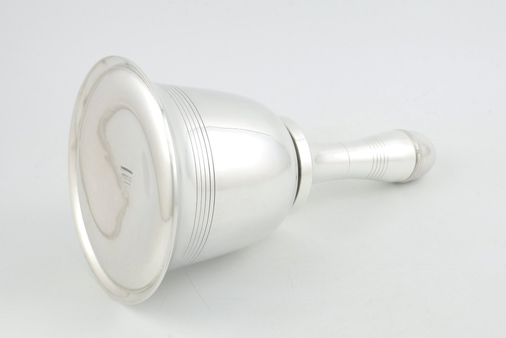 A silver plated novelty cocktail shaker in the shape of a handbell with a smooth turned handle and incised line detailing. View IX