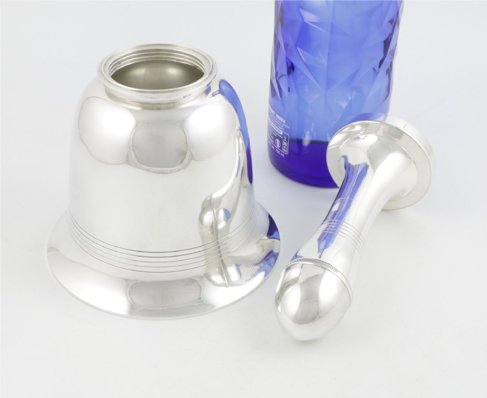 A silver plated novelty cocktail shaker in the shape of a handbell with a smooth turned handle and incised line detailing. View XI
