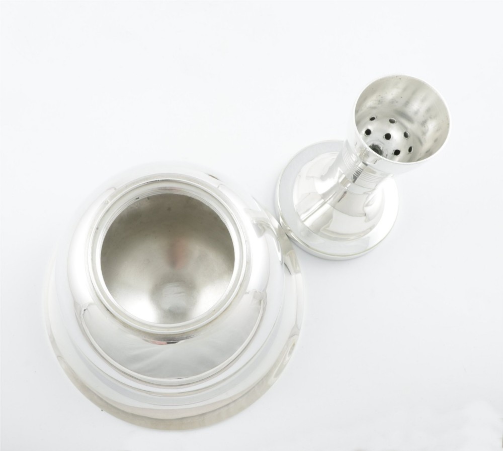 A silver plated novelty cocktail shaker in the shape of a handbell with a smooth turned handle and incised line detailing. View XII
