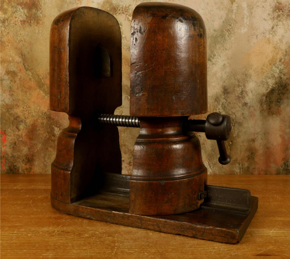 An antique French milliners hat stretcher crafted from dark polished wood with a split head block and an adjustable iron turn-screw mechanism set on a flat timber base. View III