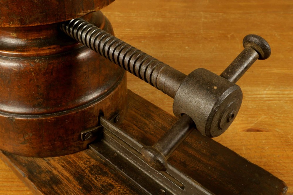 An antique French milliners hat stretcher crafted from dark polished wood with a split head block and an adjustable iron turn-screw mechanism set on a flat timber base. View VII