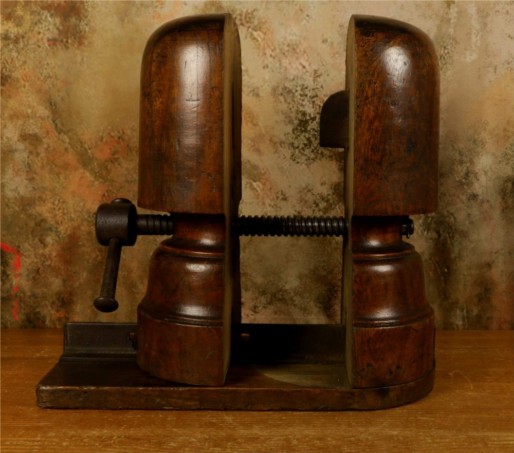 An antique French milliners hat stretcher crafted from dark polished wood with a split head block and an adjustable iron turn-screw mechanism set on a flat timber base. View IX