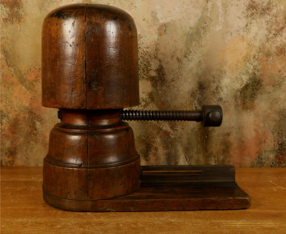 An antique French milliners hat stretcher crafted from dark polished wood with a split head block and an adjustable iron turn-screw mechanism set on a flat timber base. View X