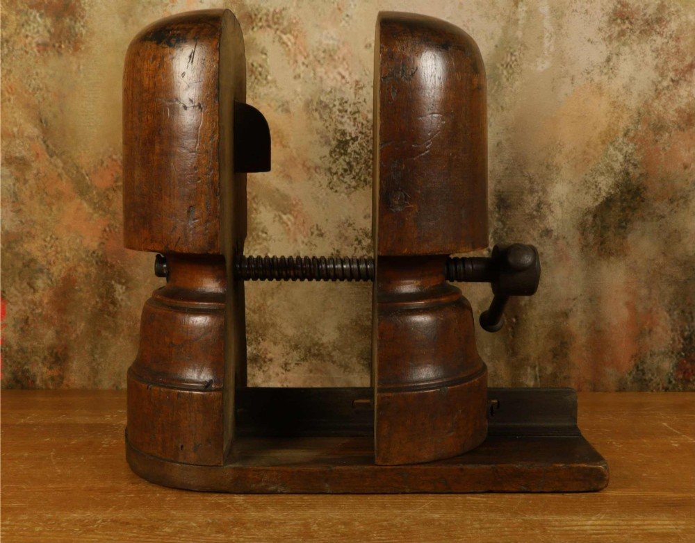An antique French milliners hat stretcher crafted from dark polished wood with a split head block and an adjustable iron turn-screw mechanism set on a flat timber base. View XII