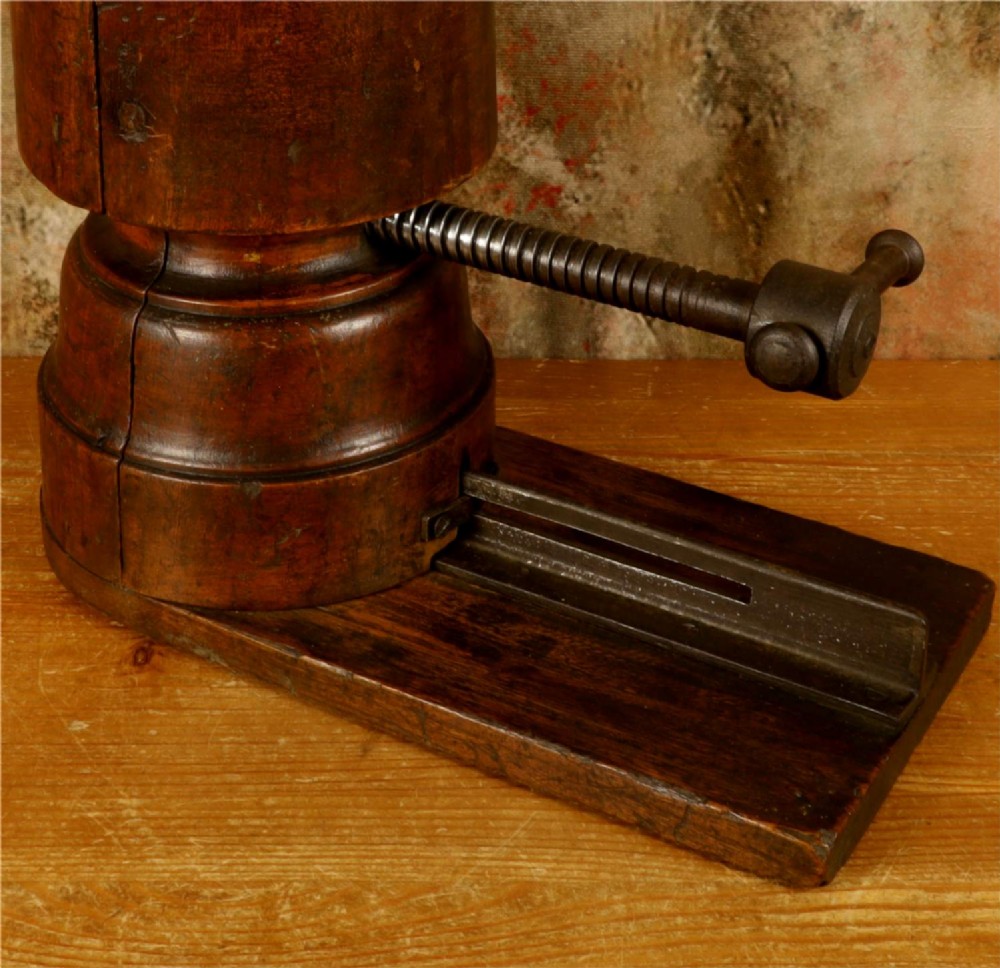 An antique French milliners hat stretcher crafted from dark polished wood with a split head block and an adjustable iron turn-screw mechanism set on a flat timber base. View XIV