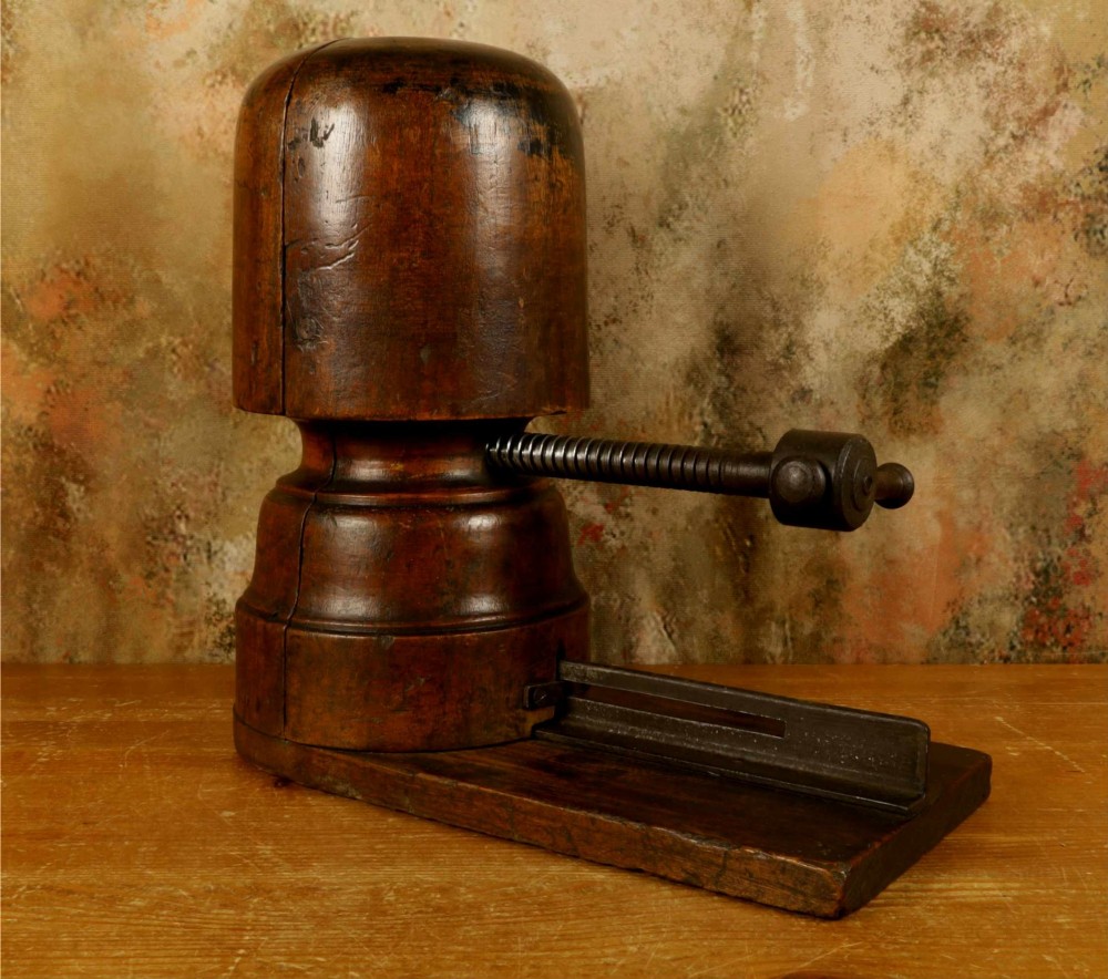An antique French milliners hat stretcher crafted from dark polished wood with a split head block and an adjustable iron turn-screw mechanism set on a flat timber base. View XV