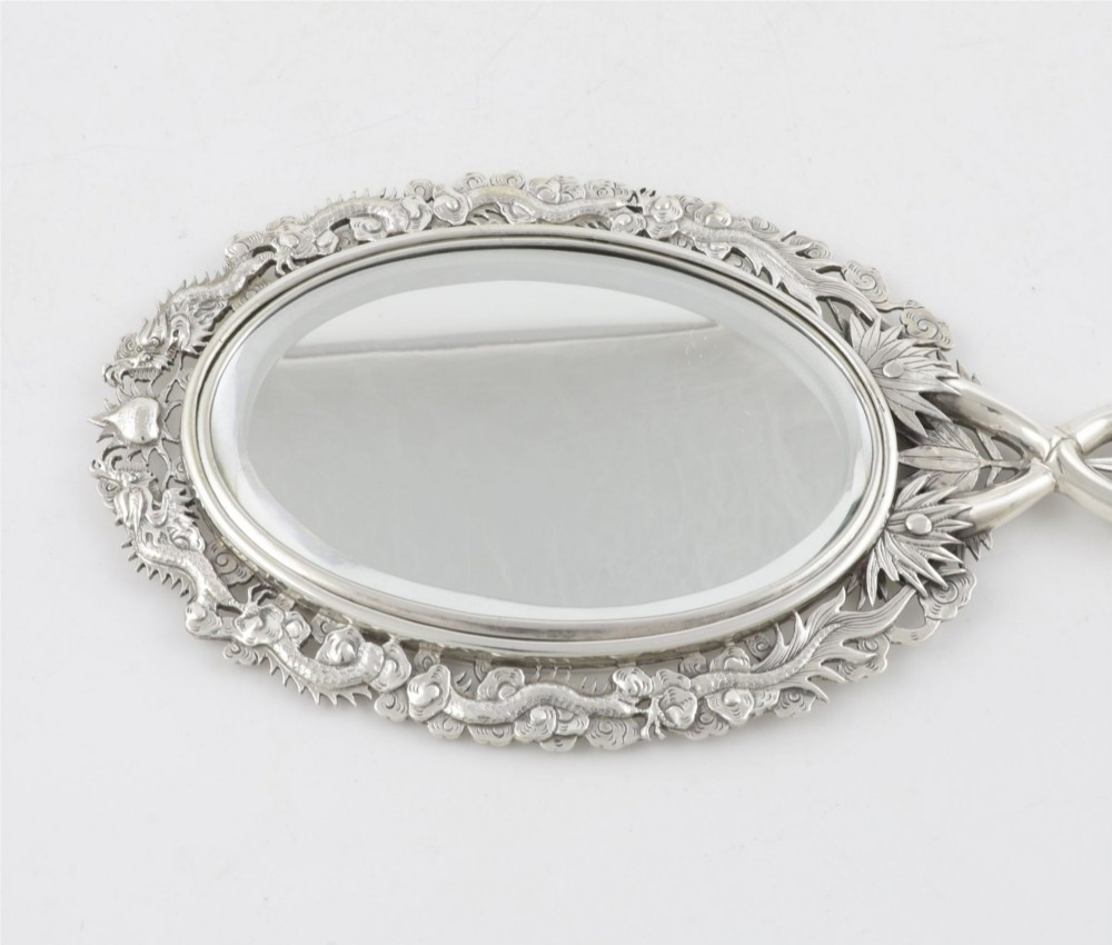 An antique silver hand mirror featuring a dragon motif frame and an interconnected faux-bamboo handle. View II