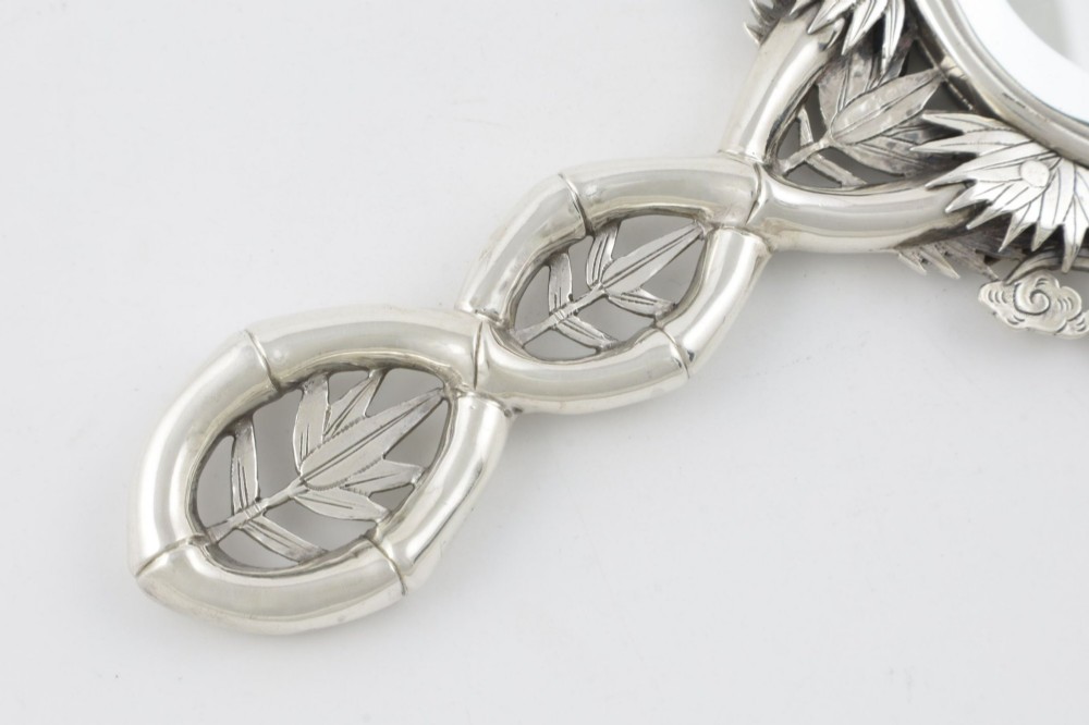 An antique silver hand mirror featuring a dragon motif frame and an interconnected faux-bamboo handle. View IV