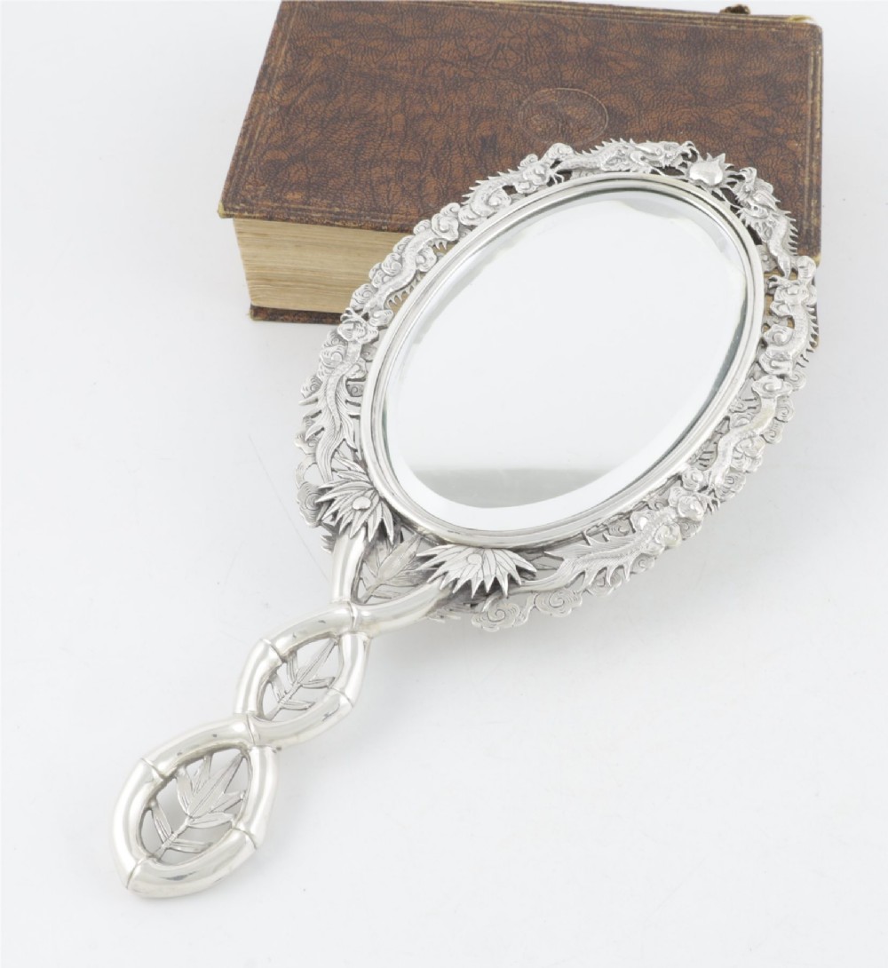 An antique silver hand mirror featuring a dragon motif frame and an interconnected faux-bamboo handle. View VI