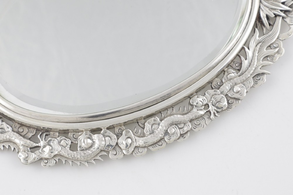 An antique silver hand mirror featuring a dragon motif frame and an interconnected faux-bamboo handle. View VII