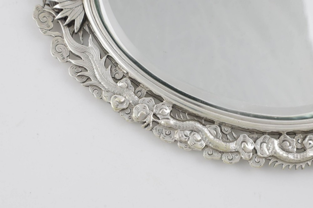 An antique silver hand mirror featuring a dragon motif frame and an interconnected faux-bamboo handle. View VIII