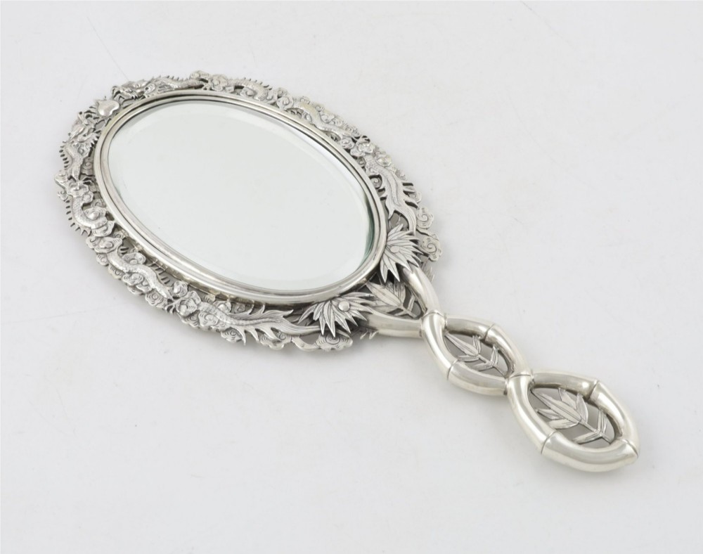 An antique silver hand mirror featuring a dragon motif frame and an interconnected faux-bamboo handle. View IX