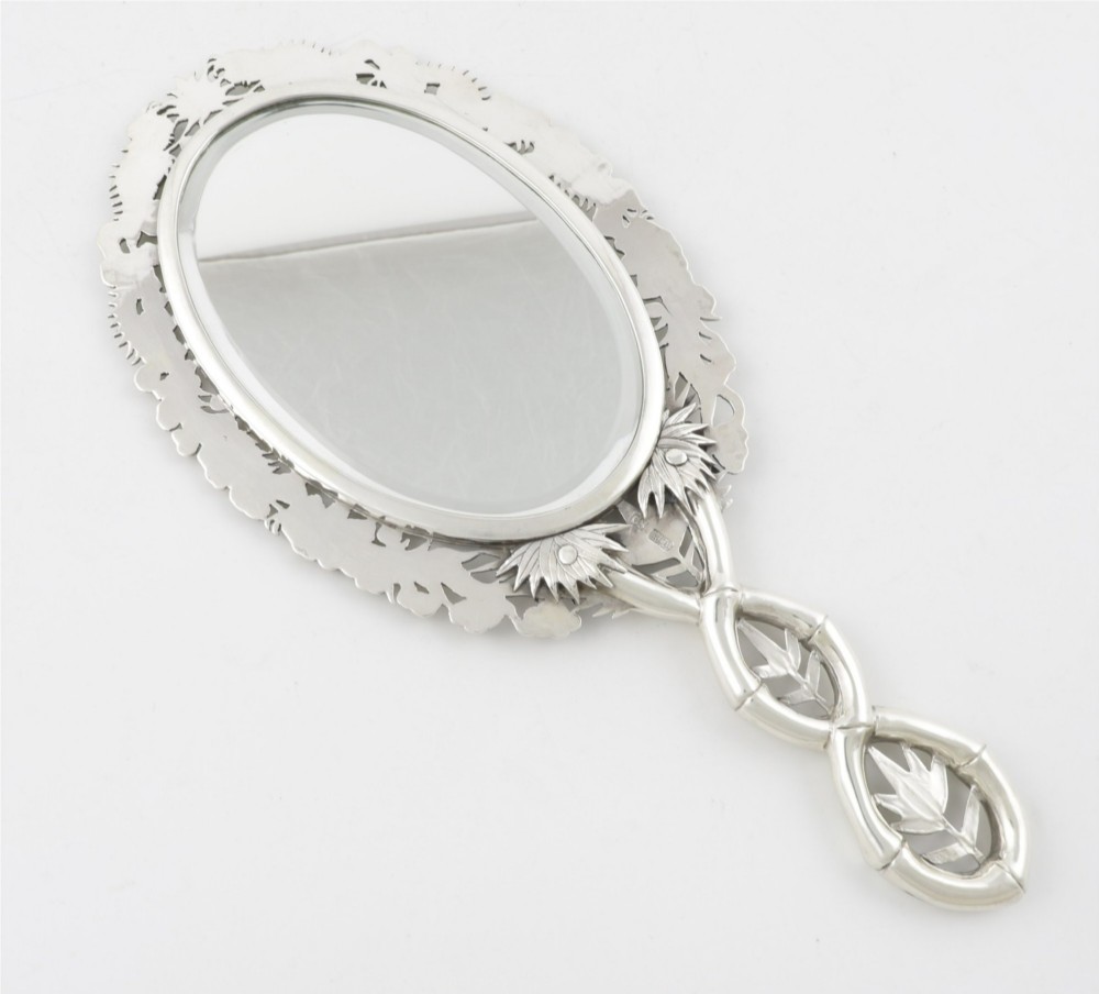 An antique silver hand mirror featuring a dragon motif frame and an interconnected faux-bamboo handle. View XII