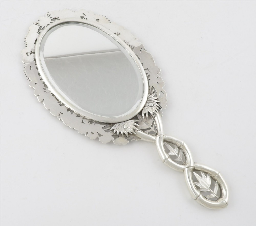 An antique silver hand mirror featuring a dragon motif frame and an interconnected faux-bamboo handle. View XIV