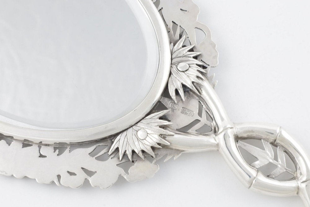 An antique silver hand mirror featuring a dragon motif frame and an interconnected faux-bamboo handle. View XV