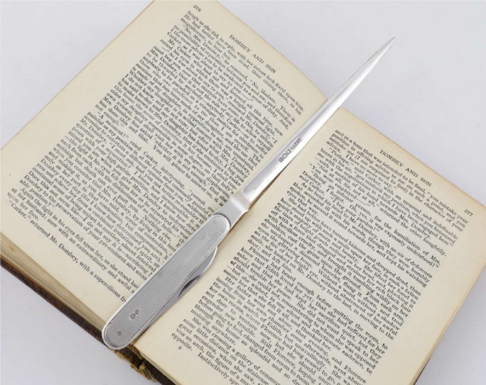 A vintage hallmarked sterling silver letter opener featuring an engine-turned handle casing with an integrated folding knife blade. View II