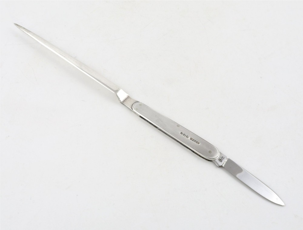 A vintage hallmarked sterling silver letter opener featuring an engine-turned handle casing with an integrated folding knife blade. View III