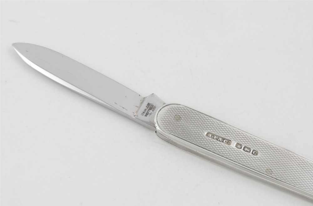 A vintage hallmarked sterling silver letter opener featuring an engine-turned handle casing with an integrated folding knife blade. View IV