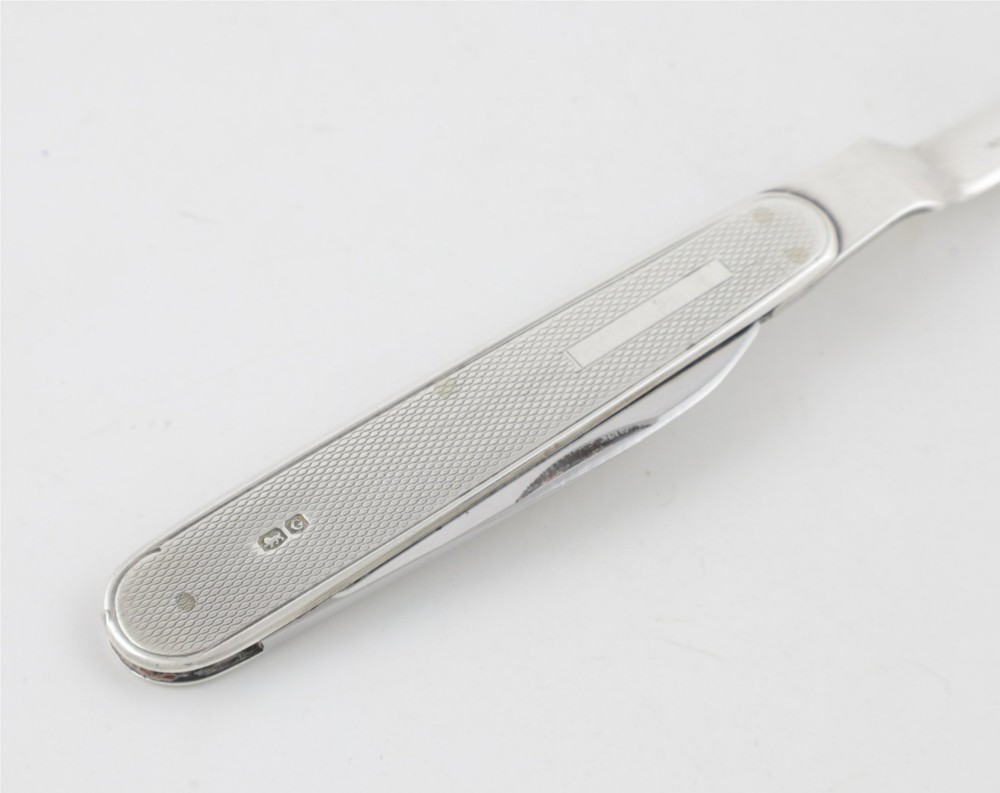 A vintage hallmarked sterling silver letter opener featuring an engine-turned handle casing with an integrated folding knife blade. View VI