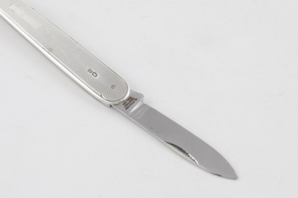 A vintage hallmarked sterling silver letter opener featuring an engine-turned handle casing with an integrated folding knife blade. View XII
