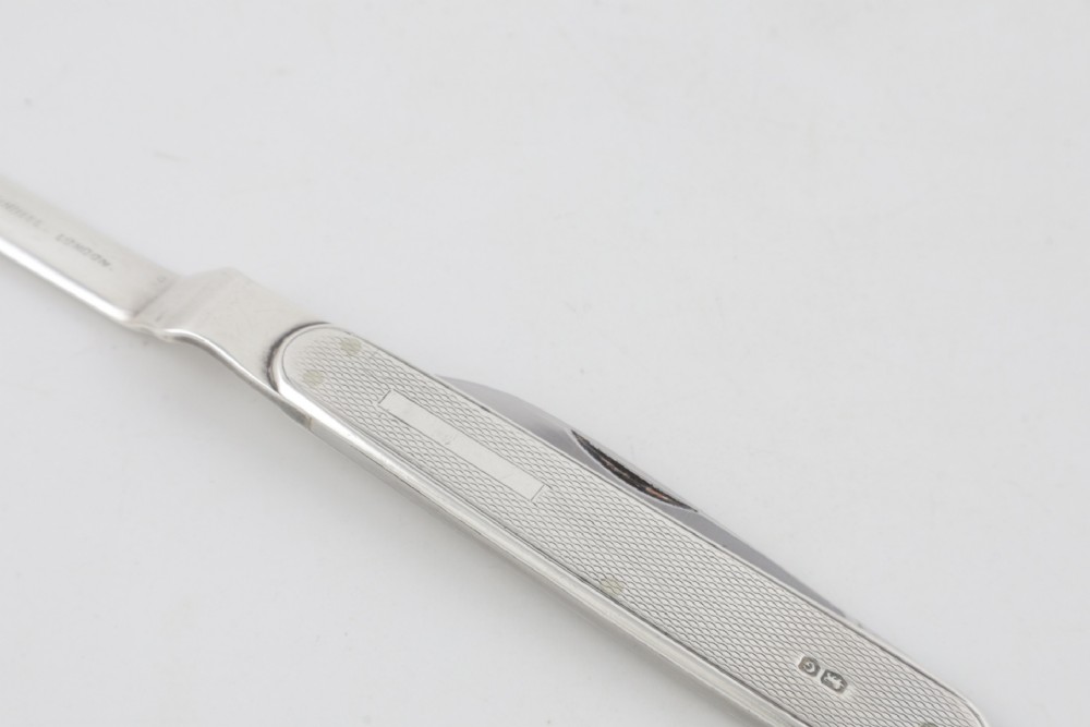 A vintage hallmarked sterling silver letter opener featuring an engine-turned handle casing with an integrated folding knife blade. View XV
