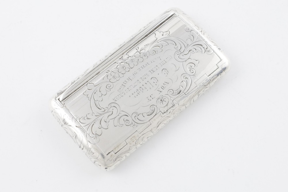 An engraved Victorian sterling silver rectangular snuff box featuring intricate foliate scrollwork and inscribed presentation text. View X