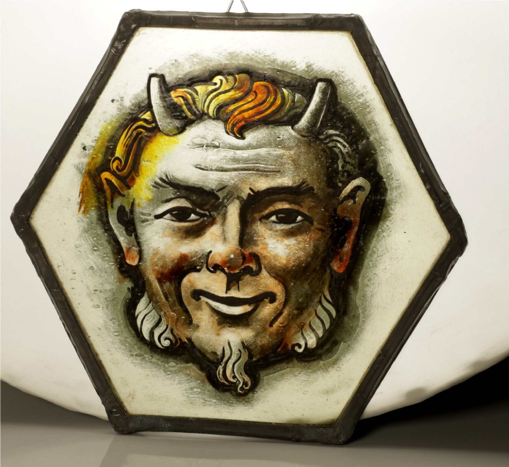 A hexagonal leaded stained glass panel featuring a hand-painted depiction of a horned devil head in grey, black, and amber tones. View II