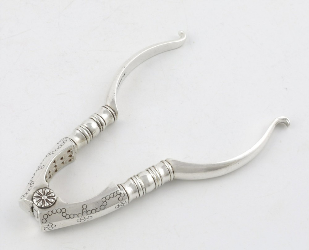 A pair of hallmarked sterling silver nutcrackers with hinged, textured jaws and curved handles featuring decorative chasing. View IV