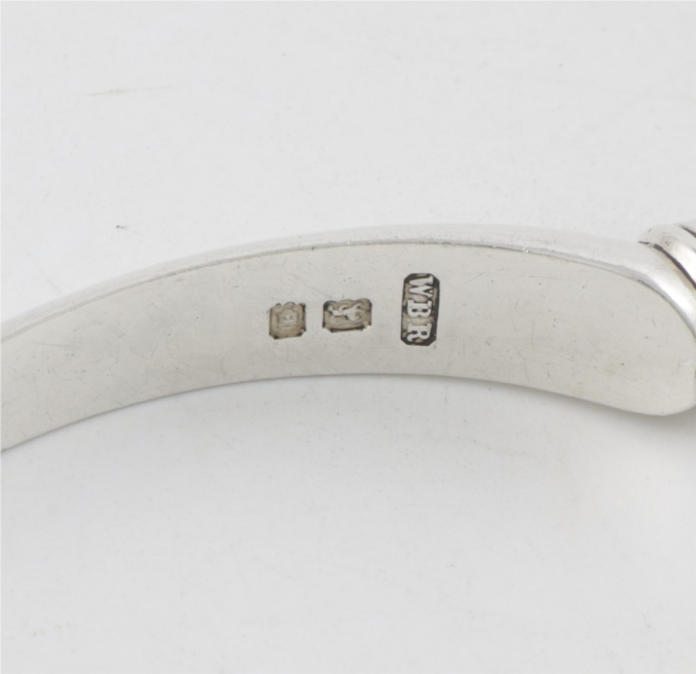 A pair of hallmarked sterling silver nutcrackers with hinged, textured jaws and curved handles featuring decorative chasing. View VII