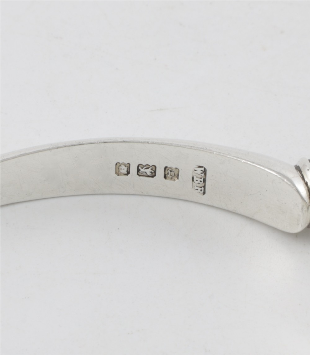A pair of hallmarked sterling silver nutcrackers with hinged, textured jaws and curved handles featuring decorative chasing. View VIII
