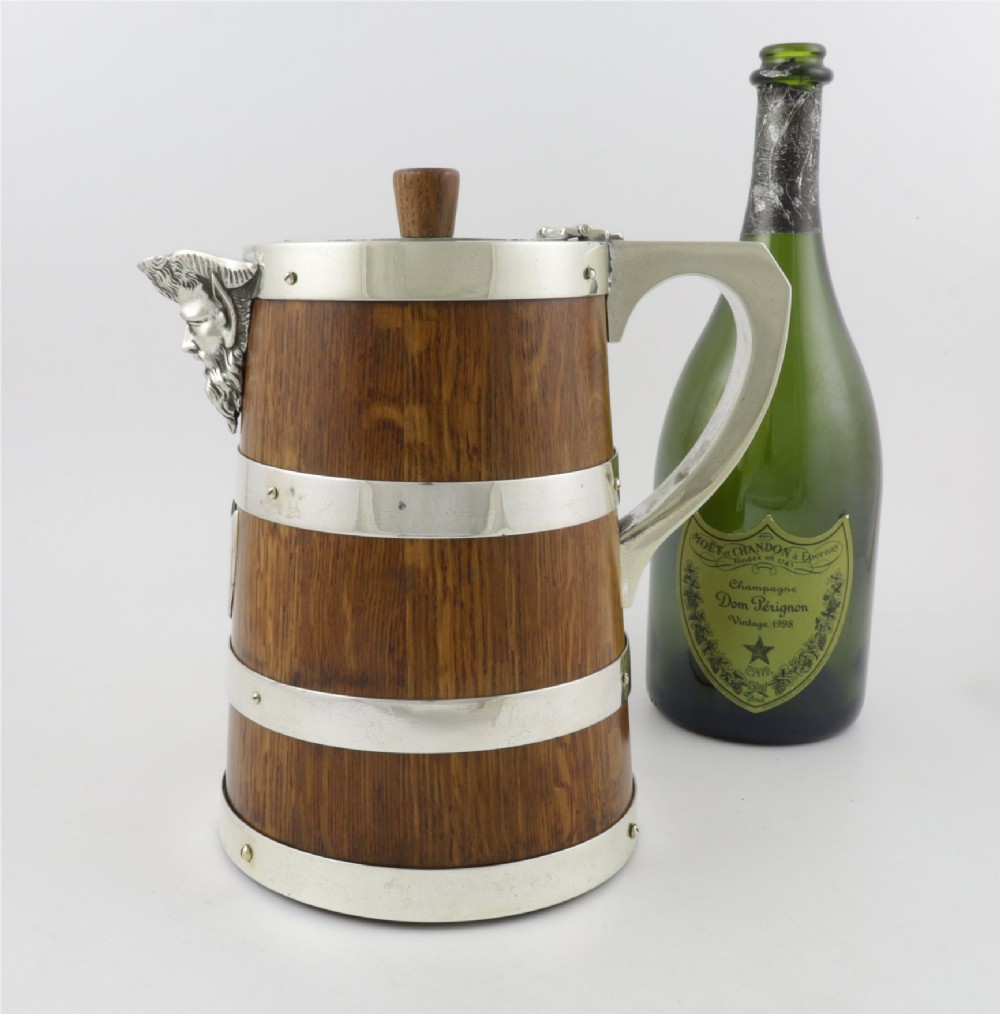 A Victorian coopered oak wine pitcher featuring silver-plated bands, a detailed Bacchus spout, and a hinged lid with a wooden finial. View IV