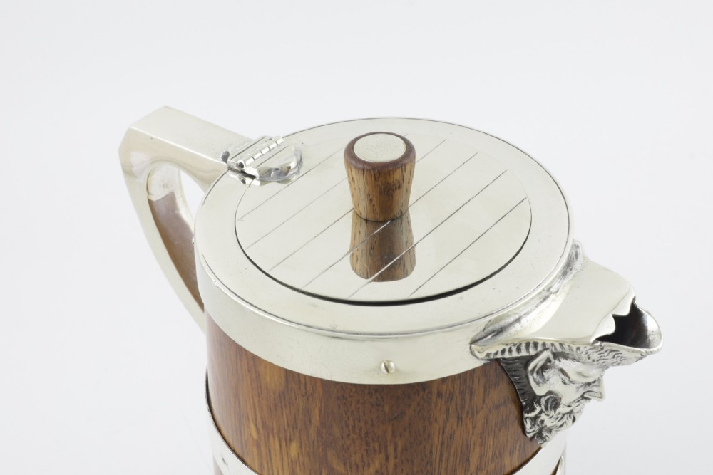 A Victorian coopered oak wine pitcher featuring silver-plated bands, a detailed Bacchus spout, and a hinged lid with a wooden finial. View VI