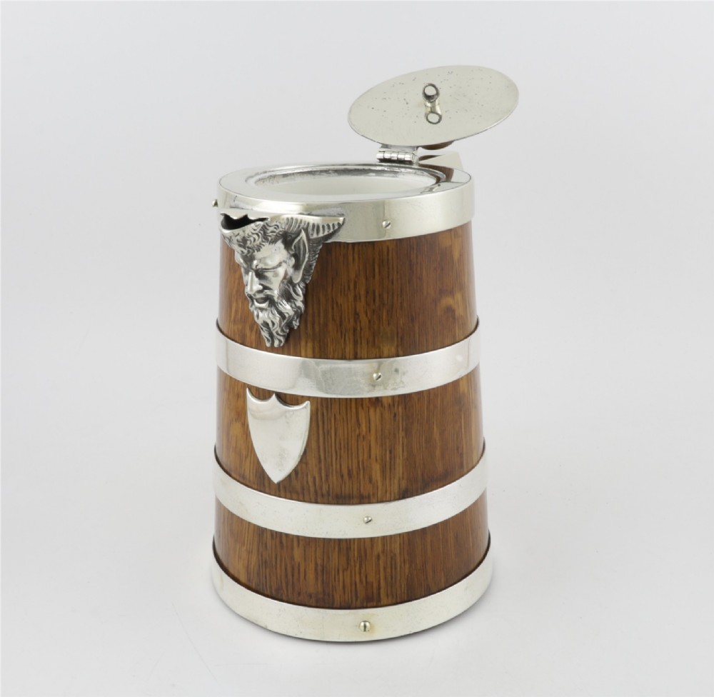 A Victorian coopered oak wine pitcher featuring silver-plated bands, a detailed Bacchus spout, and a hinged lid with a wooden finial. View VII