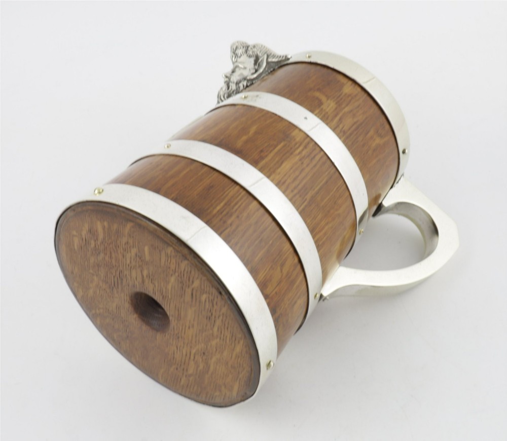 A Victorian coopered oak wine pitcher featuring silver-plated bands, a detailed Bacchus spout, and a hinged lid with a wooden finial. View VIII