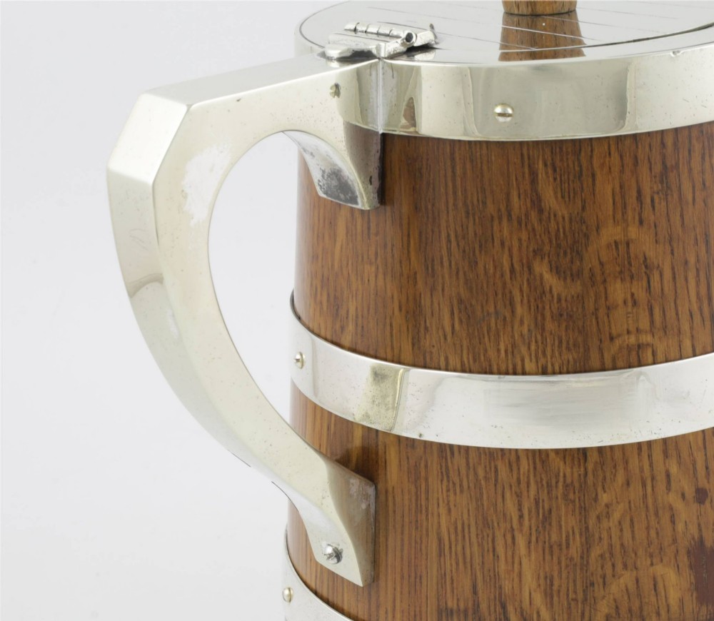 A Victorian coopered oak wine pitcher featuring silver-plated bands, a detailed Bacchus spout, and a hinged lid with a wooden finial. View X