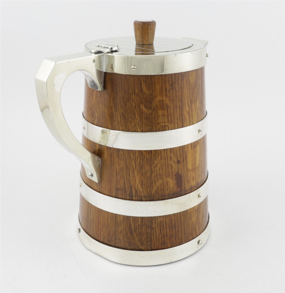 A Victorian coopered oak wine pitcher featuring silver-plated bands, a detailed Bacchus spout, and a hinged lid with a wooden finial. View XI